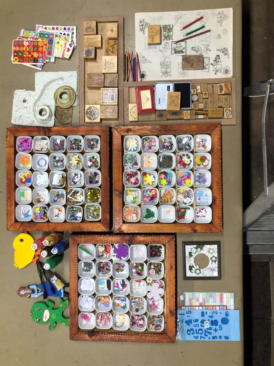 A craft table seen from above, trays of buttons, beads and pieces