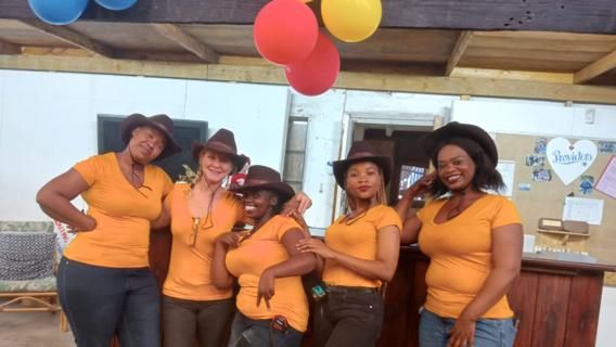 The Heart Eco sales team in orange shirts and hats, laughing under balloons