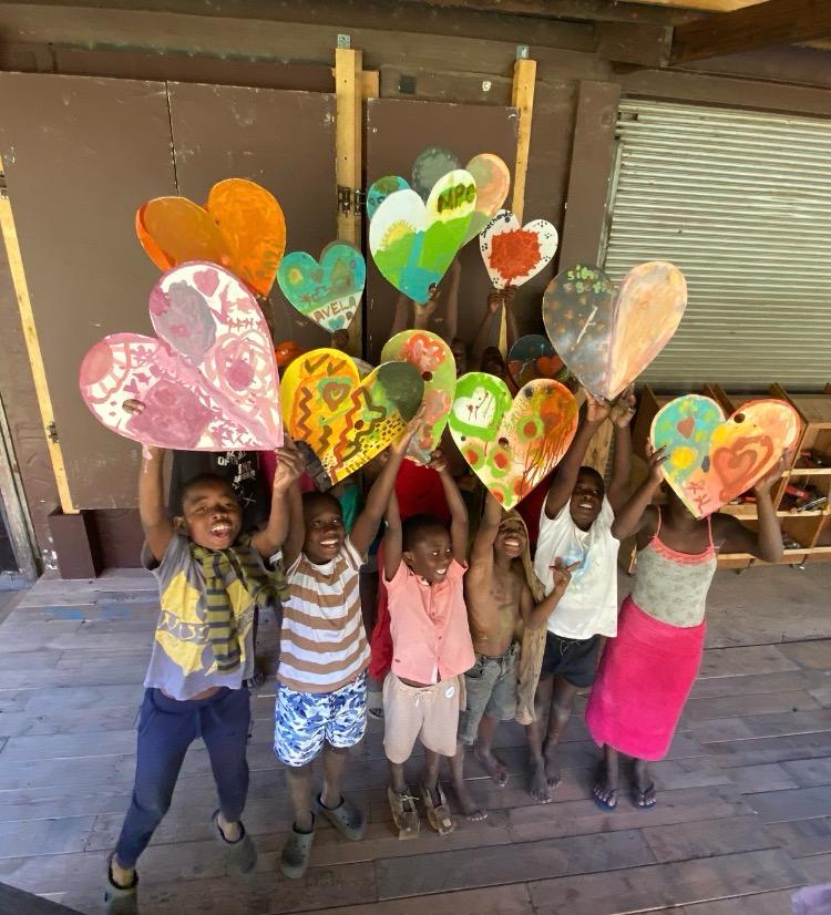 Children from Helping Hands holding up the hearts they painted