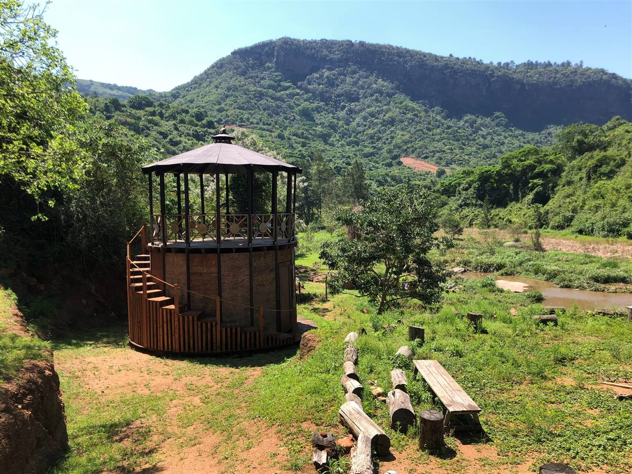 A double-storey timber rondavel in the Shongweni valley, the mountain and the river behind